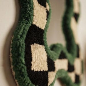 Close-up side view of a handmade tufted mirror frame showing plush New Zealand wool texture and carved edges.