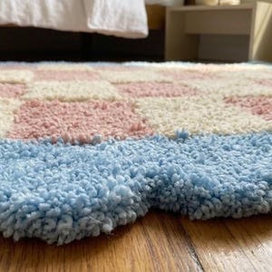 Close-up view of the scalloped blue border showing plush tufted wool texture.