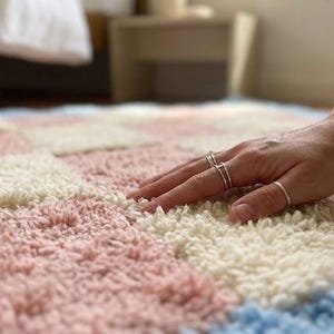 Hand touching the rug surface to demonstrate softness and plush wool texture.