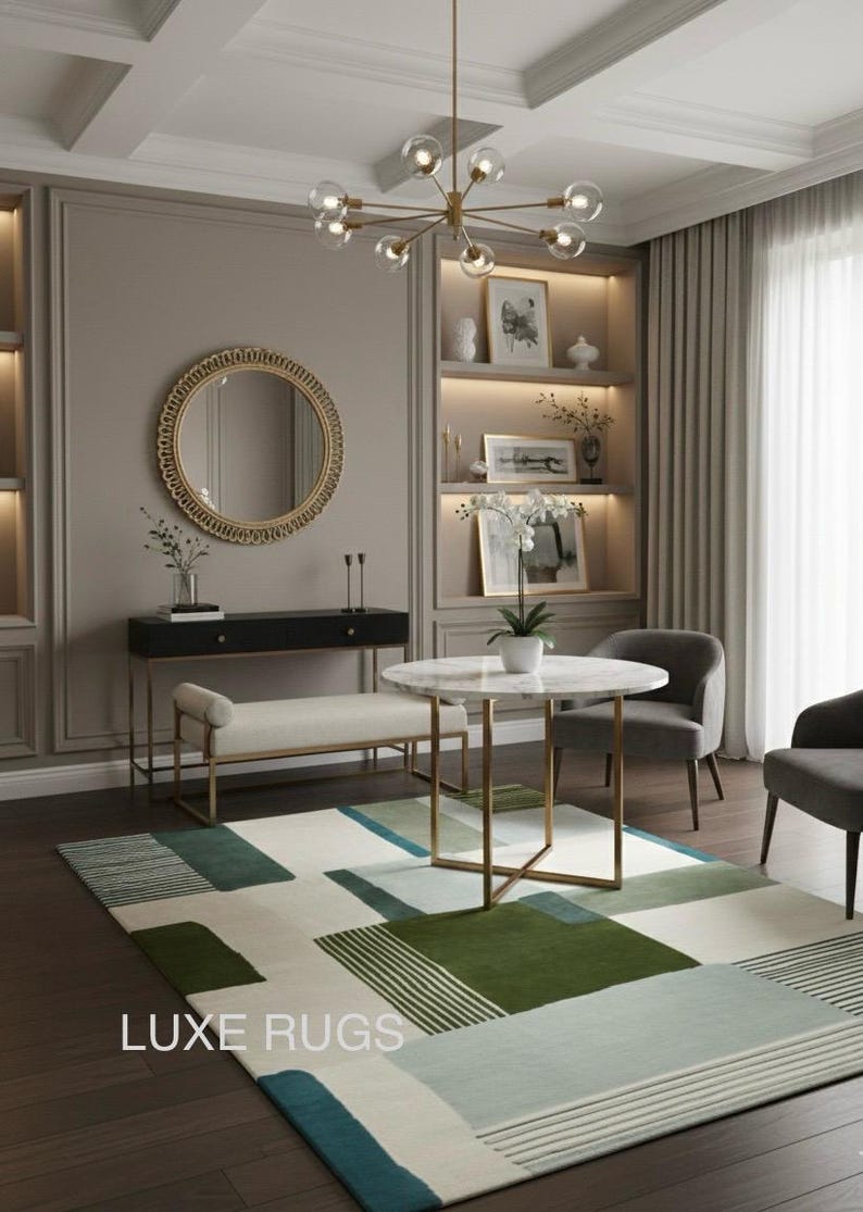 May include: A modern living room with a geometric patterned rug. The rug features green, blue, and white rectangles. A round marble table and two gray chairs are in the center. A gold chandelier hangs above. The text "LUXE RUGS" is visible.