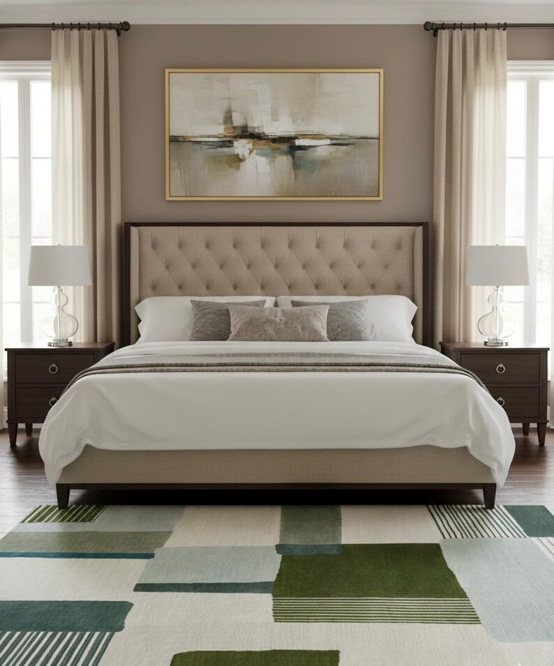 May include: A bedroom scene featuring a tufted headboard bed with white bedding and decorative pillows. Two dark brown nightstands flank the bed, each with a lamp. A large abstract painting hangs above the bed, and a patterned rug covers the floor.