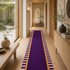 May include: A long rectangular runner rug featuring a solid deep purple center panel, a thick mustard yellow border, and an outer edge decorated with a repeating pattern of alternating purple and cream-colored vertical stripes along the perimeter.