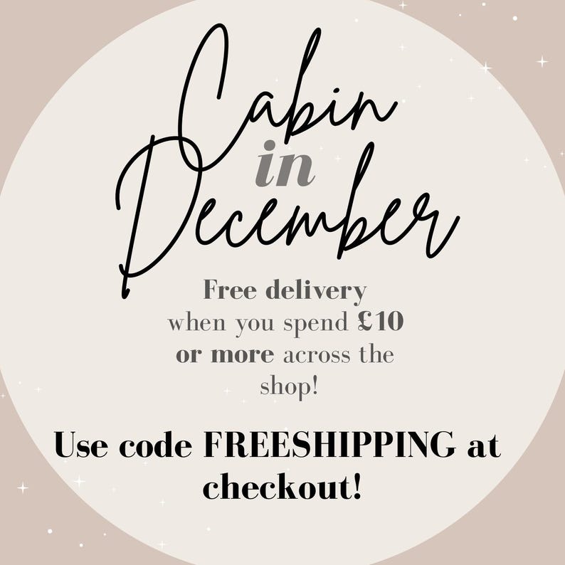 May include: A promotional graphic with the words "Cabin in December" in elegant script. The text is set against a soft beige background with subtle star accents. Additional text promotes free delivery.
