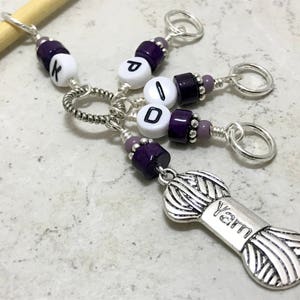 May include: Purple and silver stitch markers with letter beads spelling "PID" and a silver charm that says "yarn".