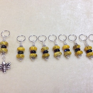 May include: Nine yellow and black bee-themed stitch markers with silver rings and a single stitch marker with a bee charm.