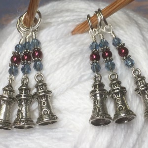 May include: Three silver lighthouse charm stitch markers with blue and burgundy beads.