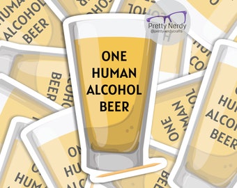 May include: A die-cut sticker featuring a tall glass filled with a golden yellow liquid. The text ONE HUMAN ALCOHOL BEER is printed in black capital letters on the glass. A small wooden toothpick is positioned horizontally at the base of the glass.