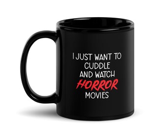 May include: Black ceramic mug with a curved handle. The mug features the text "I JUST WANT TO CUDDLE AND WATCH HORROR MOVIES" in white and red lettering. A perfect gift for horror movie fans.