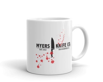 May include: White ceramic mug with a black and white graphic of a knife and the text "MYERS KNIFE CO. EST. 1963 HADDONFIELD, IL". Red blood splatter accents the graphic.