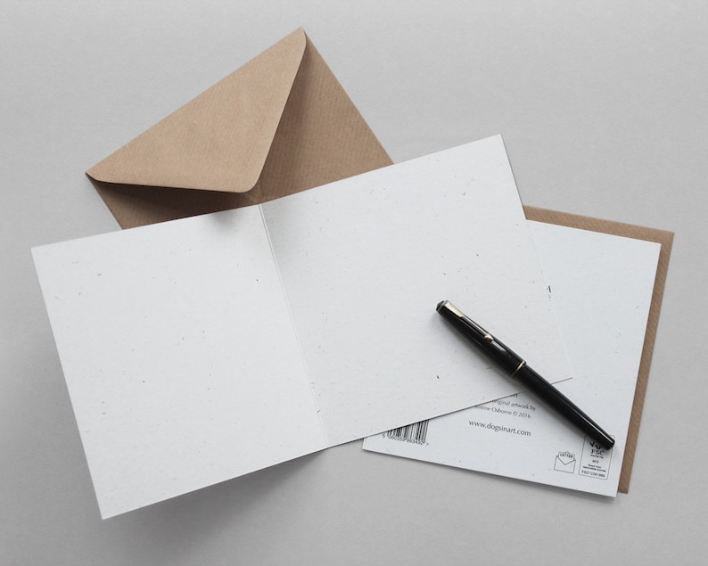 K&ouml;nnte beinhalten: Eine offene, leere Gru&szlig;karte mit einem schwarzen Stift darauf und einem braunen Umschlag. Die Karte ist wei&szlig; mit einer strukturierten Oberfl&auml;che. Der Stift ist schwarz mit silbernen Akzenten. Der Umschlag ist hellbraun.