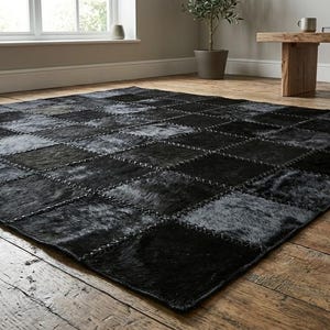 Könnte beinhalten: Ein großer, quadratischer schwarzer Teppich mit einem Patchwork-Design. Der Teppich besteht aus mehreren Quadraten aus dunklem, strukturiertem Material, die mit sichtbaren Nähten zusammengenäht sind. Der Teppich liegt auf einem Holzboden.