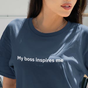 May include: A navy blue crew neck t-shirt with the text "My boss inspires me to quit" in white. The shirt is made of a soft material and has short sleeves. The shirt is a casual wear item.