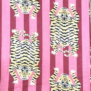 May include: A pink and burgundy striped fabric featuring a repeating pattern of stylized tigers. The tigers are yellow with black stripes and white accents. The fabric is likely used for home decor or apparel.