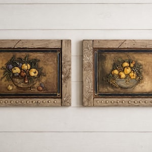 Peut inclure: Deux plaques murales rectangulaires présentant des sculptures en relief tridimensionnelles de coupes de fruits. Chaque pièce est encadrée par un cadre en bois texturé brun clair avec des feuilles sculptées et des clous circulaires.