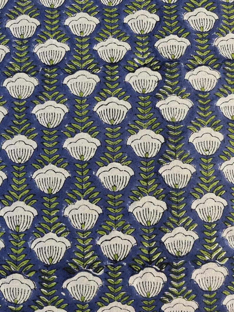 May include: A repeating pattern of white floral shapes with green leaves on a dark blue background. The floral design is evenly spaced, creating a symmetrical and visually appealing textile pattern. The fabric has a textured appearance.