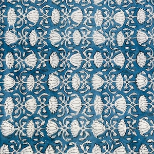 May include: A close-up of a blue fabric with a repeating white floral pattern. The design features stylized flowers and vines, creating a symmetrical and detailed print. The background is a solid, deep blue color.