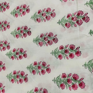 May include: White fabric with a repeating pattern of pink flowers and green leaves. The floral design is evenly spaced across the fabric, creating a visually appealing and symmetrical arrangement. The flowers are a vibrant pink, and the leaves are a soft green.