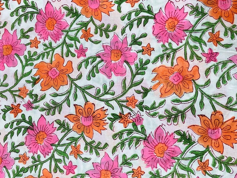 May include: Floral fabric with a repeating pattern of pink and orange flowers, green leaves, and small orange blossoms on a white background. The design is a close-up view of the fabric.