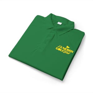 May include: Green polo shirt with a collar and three buttons. The shirt features the text "The Nerdy Golf Club" in yellow, along with a golf flag graphic. The shirt is folded neatly on a white surface.