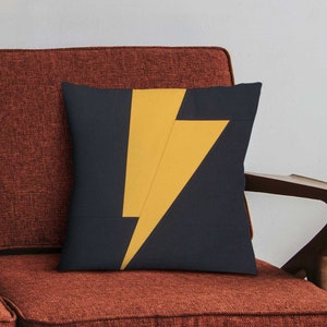 Puede incluir: Una almohada de tiro con un fondo azul oscuro y un dise&ntilde;o de rayo amarillo.