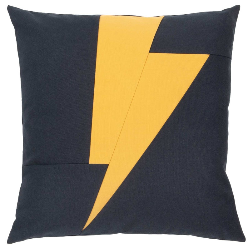 Puede incluir: Una almohada azul oscuro con un dise&ntilde;o de rayo amarillo.