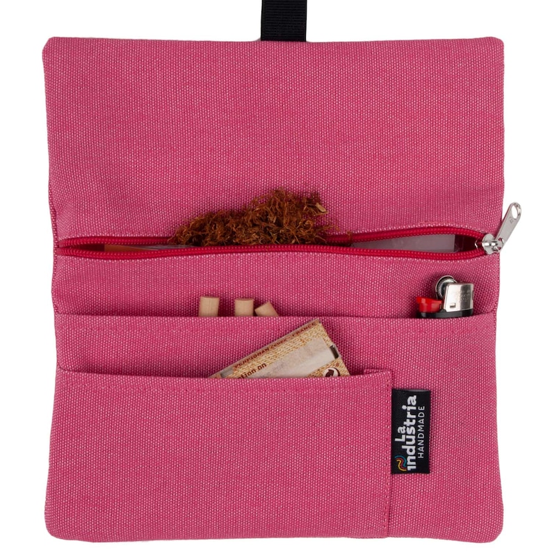 May include: A pink canvas tobacco pouch with a zipper closure. The pouch has multiple pockets and is labeled "La Industria Handmade".