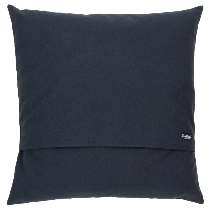 Puede incluir: Una almohada cuadrada de color azul oscuro con una peque&ntilde;a etiqueta negra que dice "walters" en letras blancas.