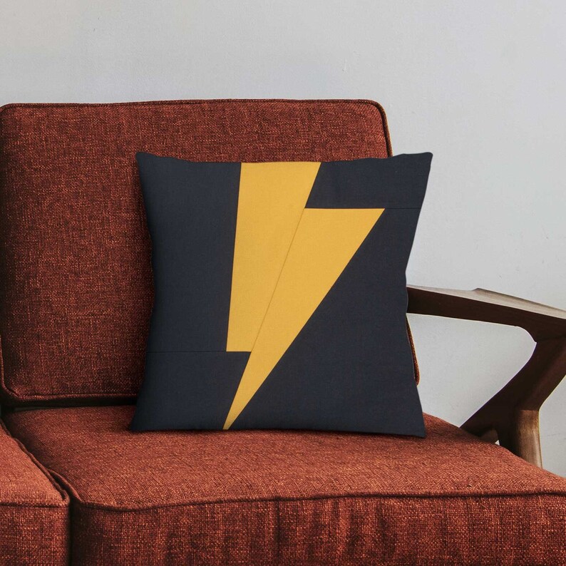 Puede incluir: Una almohada de tiro con un fondo azul oscuro y un dise&ntilde;o de rayo amarillo.