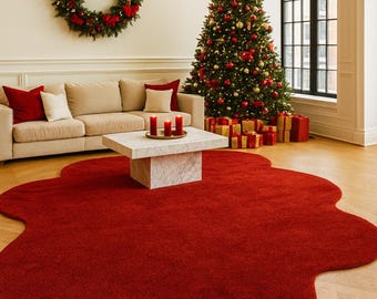 May include: A festive living room scene with a Christmas tree adorned with red and gold ornaments. A large red rug in an organic shape sits on the wooden floor. A wreath and presents add to the holiday decor.