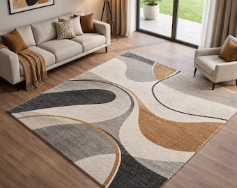 May include: A rectangular area rug featuring a large-scale abstract pattern with flowing, curved shapes in shades of cream, light gray, charcoal gray, and warm tan. The rug has a textured pile surface and covers a portion of the wooden floor.