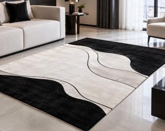 May include: A rectangular area rug featuring a high-contrast design with large, solid black sections at the corners and a central cream-colored field. The pattern is defined by flowing, curved black lines that create organic, wave-like shapes.