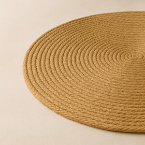 Puede incluir: Un salvamanteles redondo de color beige c&aacute;lido. Est&aacute; hecho de cuerda trenzada apretada, creando una superficie texturizada. El dise&ntilde;o presenta c&iacute;rculos conc&eacute;ntricos, agregando inter&eacute;s visual. Ideal para el comedor y la decoraci&oacute;n del hogar.