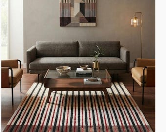 May include: A rectangular area rug featuring a pattern of vertical stripes in shades of black, red, and cream. The design includes a section with thin, repeating lines that transition into a broader, darker striped section at the bottom edge.