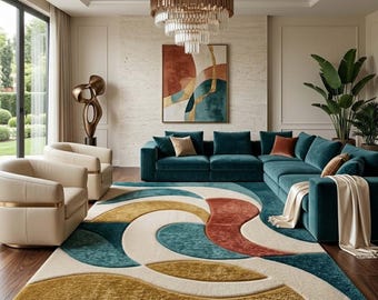 May include: A large area rug featuring a textured, abstract pattern of curved shapes in teal, mustard yellow, cream, and burnt orange. The rug is placed on a dark wood floor in a room with a teal sectional sofa, two cream armchairs, and a chandelier.