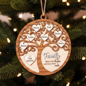 May include: A wooden family tree Christmas ornament. The ornament is round with a tree design, featuring names in heart-shaped leaves. The text "Family" and a quote are also included. The ornament hangs from a natural twine string.