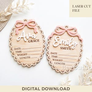 May include: Two oval wooden birth announcement signs with scalloped edges, each featuring a light pink 3D bow at the top. The signs display the names Ava Grace and Emily Smith in white script, with engraved lines for date, time, weight, and length.