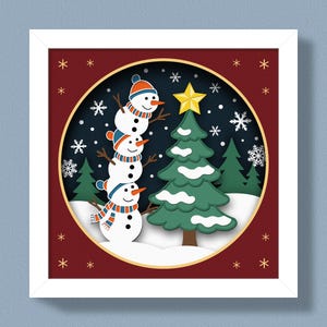 May include: A framed Christmas-themed artwork featuring a stacked snowman with a hat and scarf, a green Christmas tree with a gold star, and snowflakes against a dark blue background. The artwork is set within a red border with white stars.