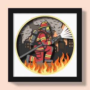 May include: A framed paper art piece showing a firefighter in red and yellow gear tackling a fire. The artwork features a kneeling firefighter with a hose, flames at the bottom, and a city silhouette. The artwork is in a black frame.