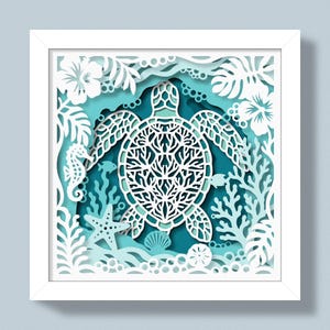 Peut inclure: Une œuvre d'art en papier superposé dans un cadre blanc carré, représentant une silhouette de tortue marine blanche centrale entourée de découpes complexes de fleurs tropicales, feuilles de monstera, hippocampe, étoile de mer, corail et bulles sur fond bleu sarcelle.