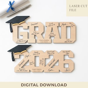 Op de afbeelding: Houten afstudeerdecoratie met het woord "GRAD" en de cijfers "2026". Het ontwerp bevat afstudeerpetten, felicitaties en de naam "EMILY SMITH". De woorden "LASER CUT FILE" en "DIGITAL DOWNLOAD" zijn ook zichtbaar.