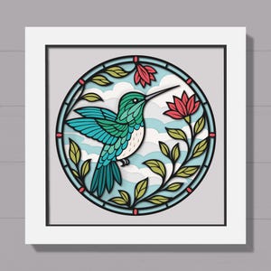 Puede incluir: Una obra de arte en papel enmarcada y en capas que presenta un colibrí en un diseño circular. El ave tiene alas turquesas y azules y un pico largo. Flores rojas y hojas verdes rodean al ave, sobre un fondo de cielo azul claro y blanco.