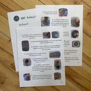 May include: Two sheets of paper with instructions for a pottery project, titled "OB01 - Building Instructions." The instructions include diagrams and text, with steps for creating a small cone and other pottery shapes. The papers are on a wooden surface.