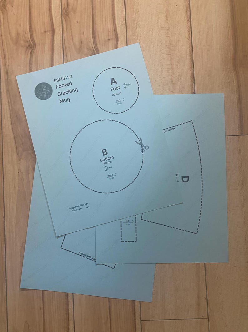 May include: Light blue paper templates for a footed stacking mug, labeled FSM01V2. The sheets feature printed diagrams with dashed cutting lines, scissors icons, and labels including A Foot, B Bottom, and D. Text includes 100% scale and suggested slab thickness.