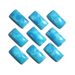 May include: Nine rectangular, polished gemstones in shades of light blue and white. The stones have a smooth, glossy surface and a marbled appearance. The gemstones are arranged in a grid pattern against a white background.