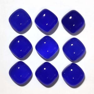 Puede incluir: Nueve gemas cuadradas pulidas en varios tonos de azul. Cada gema tiene esquinas redondeadas y una superficie brillante, que refleja la luz. Las gemas est&aacute;n dispuestas en una cuadr&iacute;cula de tres por tres, mostrando su color y forma.