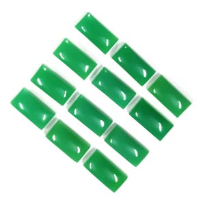 May include: A selection of rectangular, polished green gemstones displayed diagonally against a white backdrop. The gemstones have a glossy finish and are evenly spaced, highlighting their vibrant colour and shape. Suitable for jewellery making or other crafts.