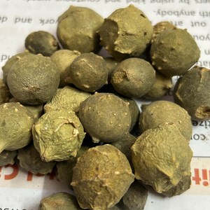 Puede incluir: Primer plano de un conjunto de peque&ntilde;os objetos redondos, de color verde oliva, con superficies texturizadas. Los objetos est&aacute;n agrupados, llenando el encuadre. La iluminaci&oacute;n resalta las texturas y formas variadas.