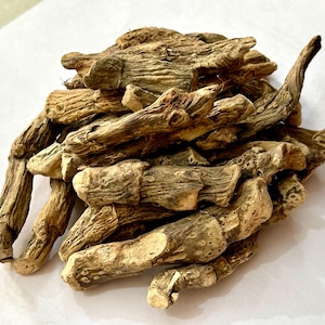 May include: A pile of dried, light brown roots with a rough, textured surface. The roots vary in size and shape, with some appearing thicker and more bulbous, while others are more slender and elongated. The overall color is a natural, earthy tone.
