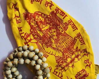 Könnte beinhalten: Ein gelbes Tuch mit roter Schrift und einer roten Illustration von zwei Figuren. Eine Kette aus hellfarbigen Perlen mit einer gelben Quaste ist ebenfalls vorhanden. Auf dem Tuch steht der Text "Hare Krishna Hare Krishna Krishna Krishna Hare Hare".