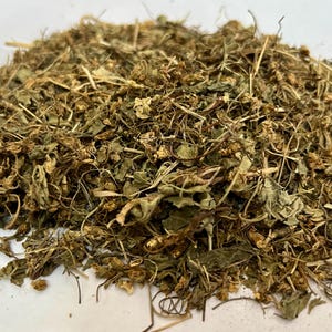 May include: A close-up shot of a pile of dried herbs and leaves. The color palette is dominated by shades of brown and green, with a mix of textures from the dried plant matter. The image suggests a natural, organic product, possibly for culinary or medicinal use.